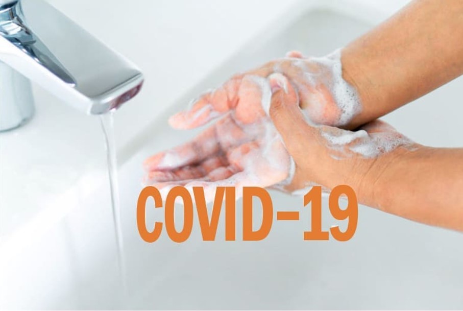 Henkilö pesee käsiään vesihanan alla. Kuvassa lukee teksti: Covid-19.