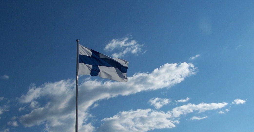 Suomen lippu, taustalla sininen taivas.