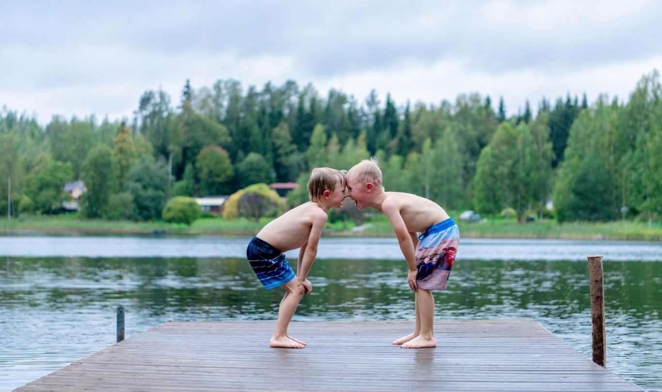 Kaksi poikaa laiturilla, taustalla järvi.