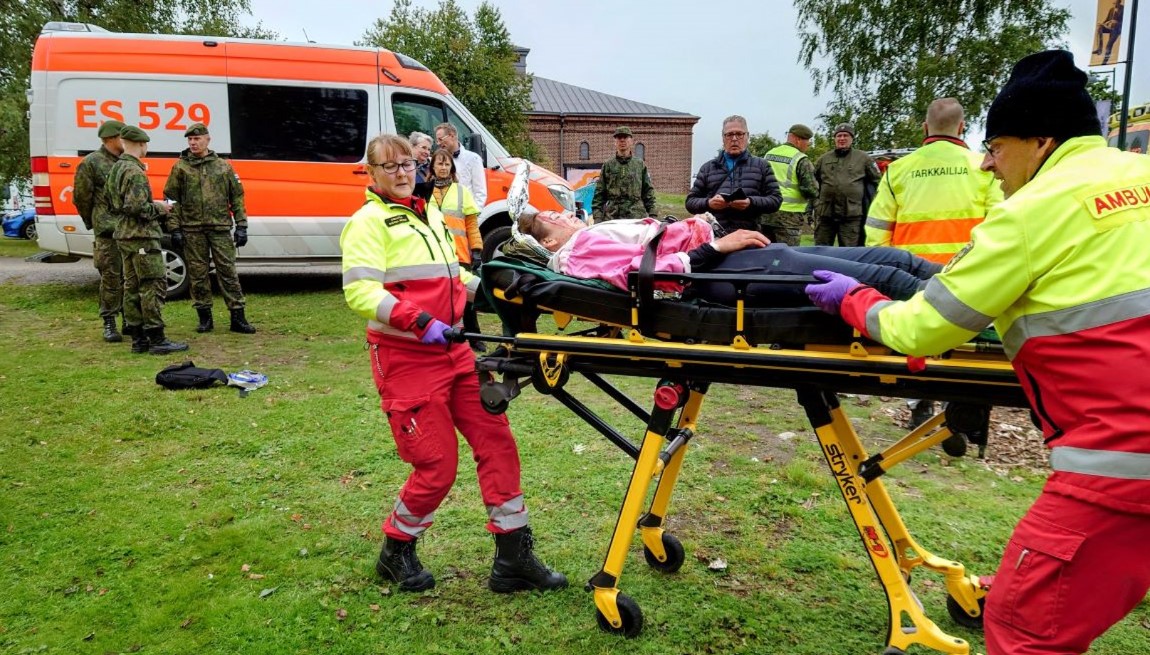 Potilas paareilla, taustalla ambulanssi.