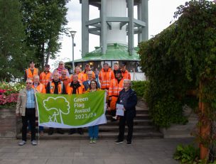 Puistotyöntekijöitä vihreän lipun kanssa, taustalla Naisvuoren torni.