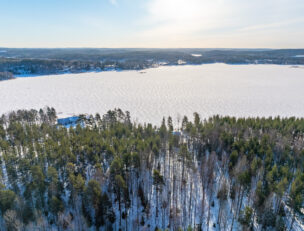 Ilmakuva järvimaisemasta, etualalla metsäistä maisemaa.