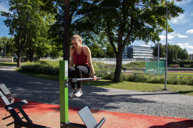 Nainen ulkokuntosalilaitteella.