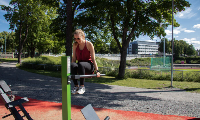 Nainen ulkokuntosalilaitteella.