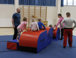 Aikuisia ja lapsia liikuntasalissa.