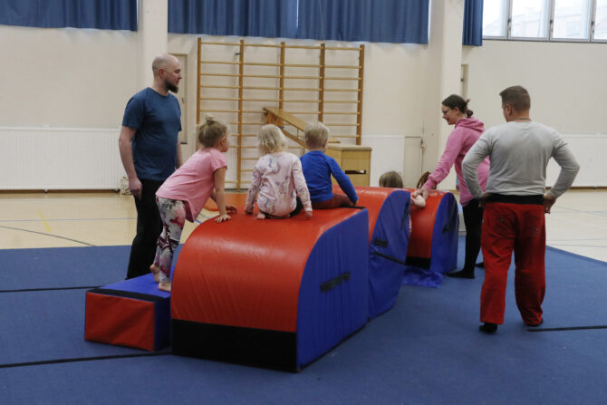 Aikuisia ja lapsia liikuntasalissa.