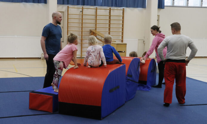 Aikuisia ja lapsia liikuntasalissa.