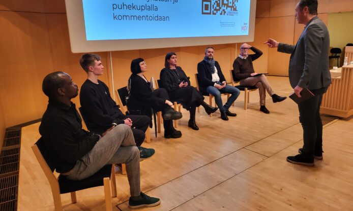 Keskustelijoita istumassa.