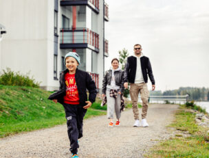 Lapsi juoksee, taustalla kaksi aikuista.