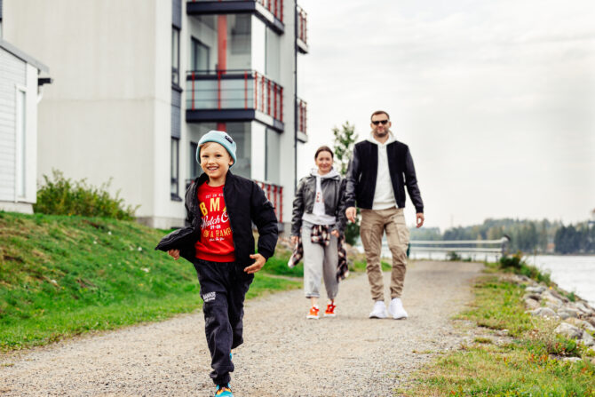 Lapsi juoksee, taustalla kaksi aikuista.