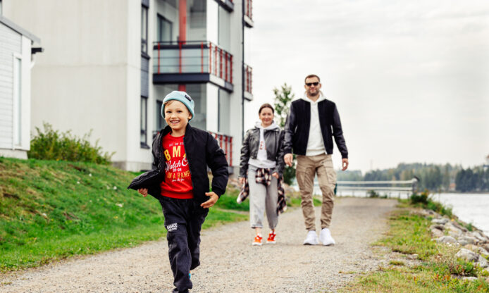 Lapsi juoksee, taustalla kaksi aikuista.