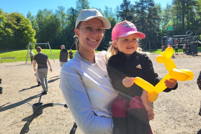 Nainen sylissään lapsi leikkipuistossa.